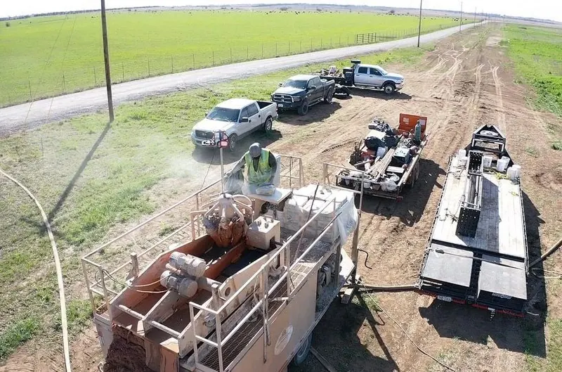 Aerial view of a Punch Out Drilling HDD jobsite with drill rig, trucks and equipment along a road
