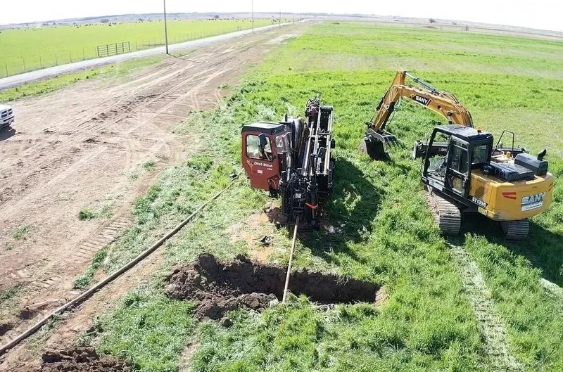HDD drill rig and excavator working a bore in an open field